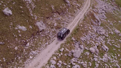 Top-down-of-Motorhome-on-dirt-track-at-Durmitor-National-Park-Montenegro,-aerial
