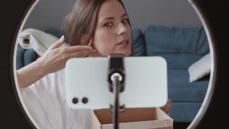 young cute vlogger woman testing a wooden gua on her face while recording and giving her feedback