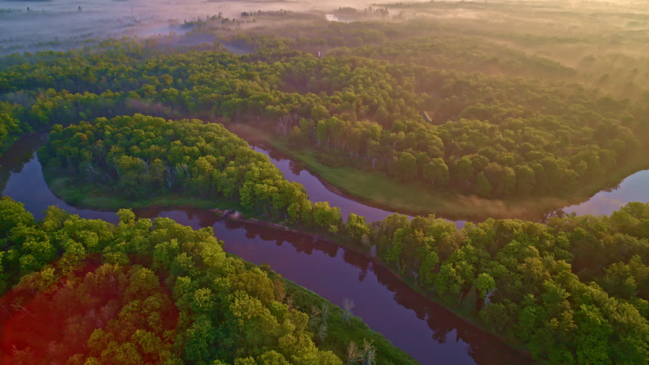 drone shot panning and twisting over large horseshoe shaped curve of the Manistee river in the upper peninsula of michigan on a foggy morning in summer