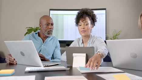 diverse business people using laptops at conference table with copy space