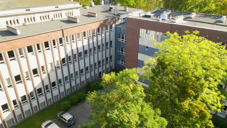 Slow-Aerial-in-Faculty-of-Management-University-of-Gdansk,-close-up-green-trees-in-autumn-season