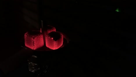 smoking hookah, shisha, water pipe. red glowing charcoals on a hookah at night. hot red coals hookah with sparks on shisha on a dark background. the pleasure of smoking water pipe.