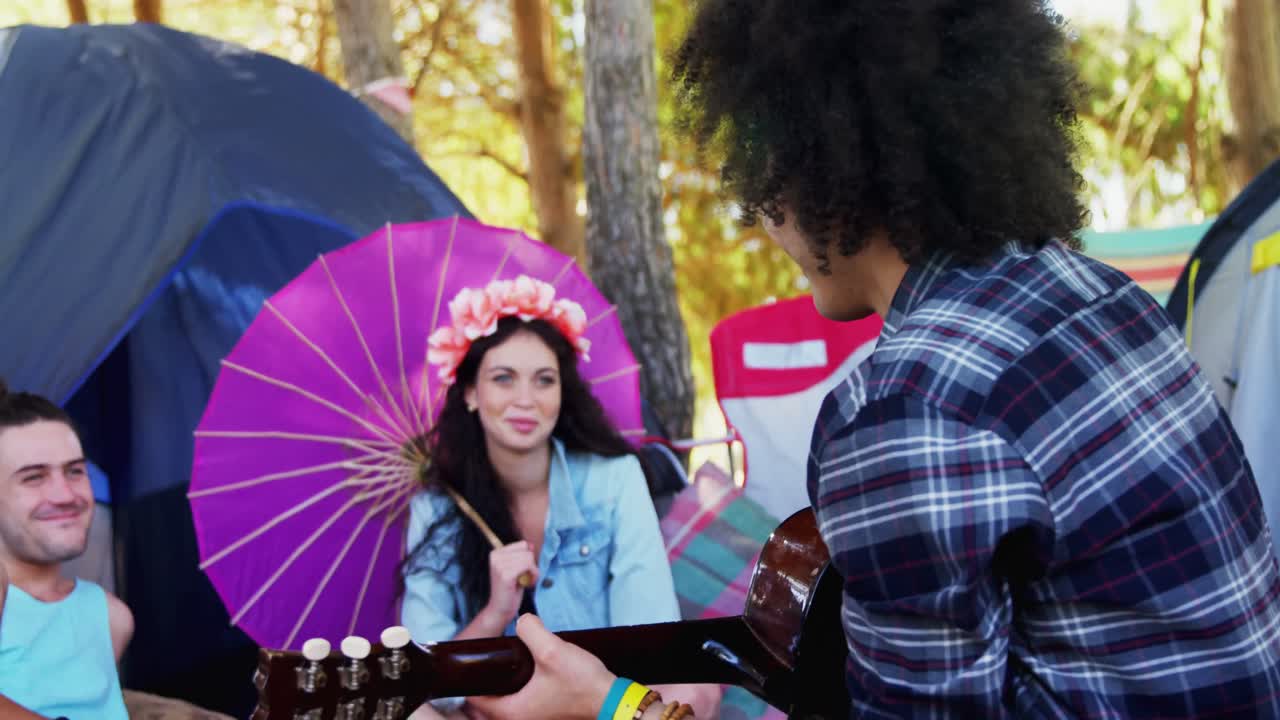 hombre tocando la guitarra para sus amigos en un festival de música 4k