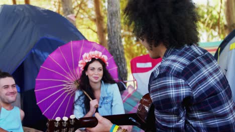 man playing guitar for his friends at a music festival 4k