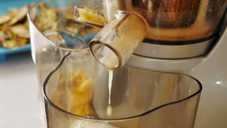 pineapple juice flowing out of a masticating juice machine