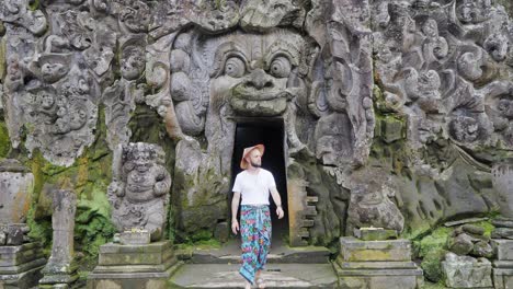 journey into mystery: male tourist dressed in traditional balinese sarong explores goa gajah elephant cave, one of the holiest temples in ubud, bali