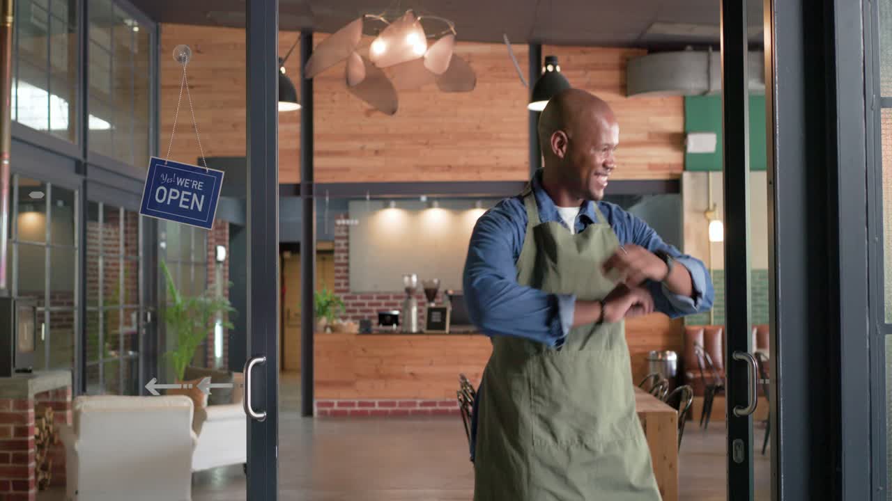 Afrikanischer Mann mit grüner Schürze geht zu Glastüren, wechselt Schild von „Geschlossen“ zu „Geöffnet“ und öffnet das Café.