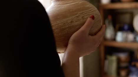 Close-Up-Footage-Of-Female-Potter-Putting-Handmade-Vase-On-Shelf-In-Studio,-Pleased-With-Her-Work,-Smiling-To-The-Camera