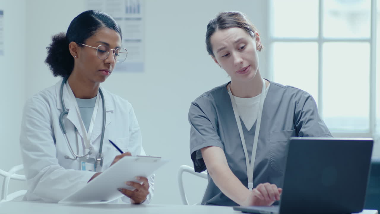 두 명의 여성 의사가 의료 사무실에서 노트북으로 일하고 있습니다.