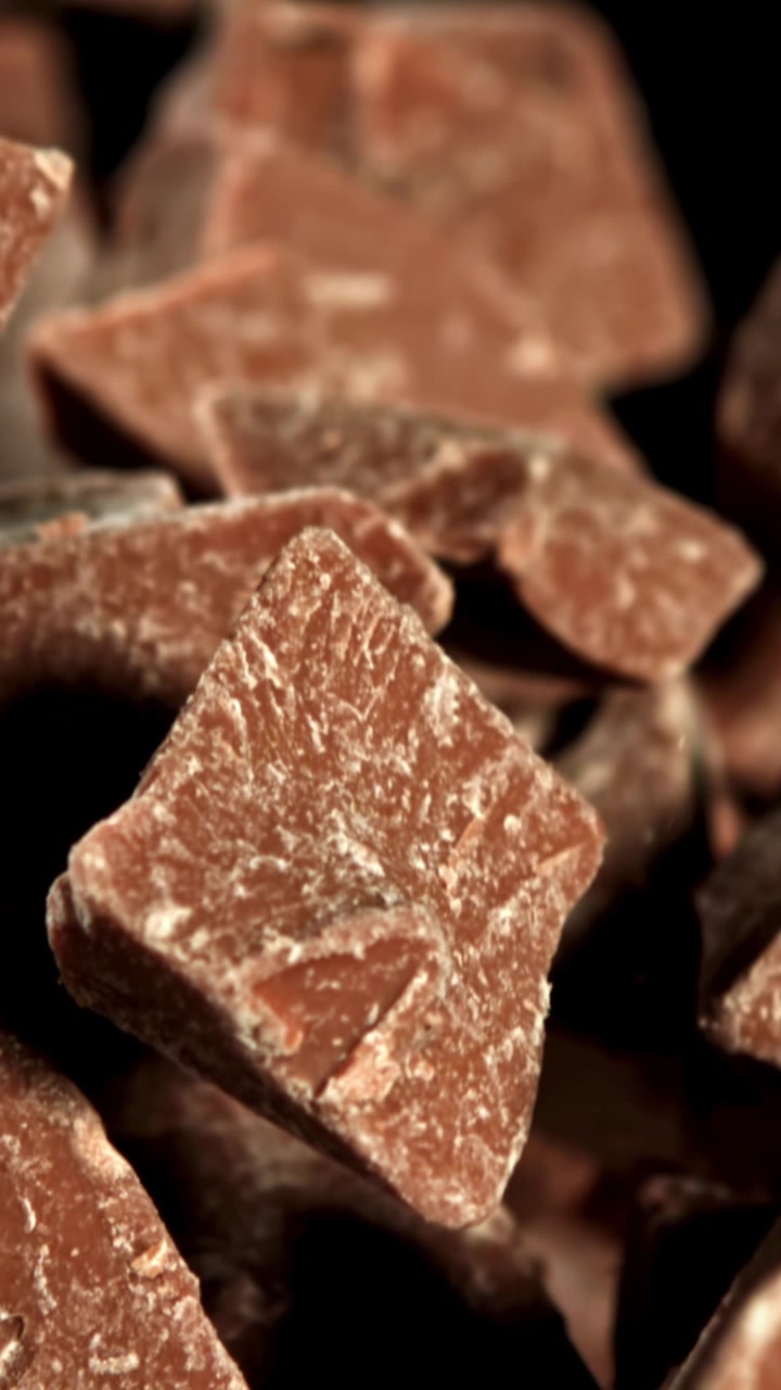 Slow Motion Close-Up of Chocolate Pieces Falling with Dust