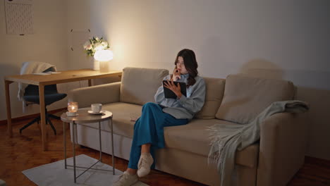 businesswoman reading tablet evening at room. serious woman working sitting sofa