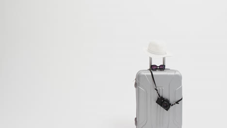 close up of suitcase, camera, sunglasses and sunhat with copy space on white background