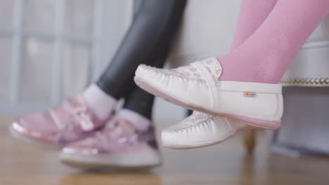 children's feet in pink socks and white loafers on a sofa