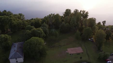 Una-Impresionante-Vista-Desde-Un-Dron-De-La-Aldea-De-Katvari-Al-Atardecer,-Destacando-El-Tilo-Katvari-Junto-Al-Lago