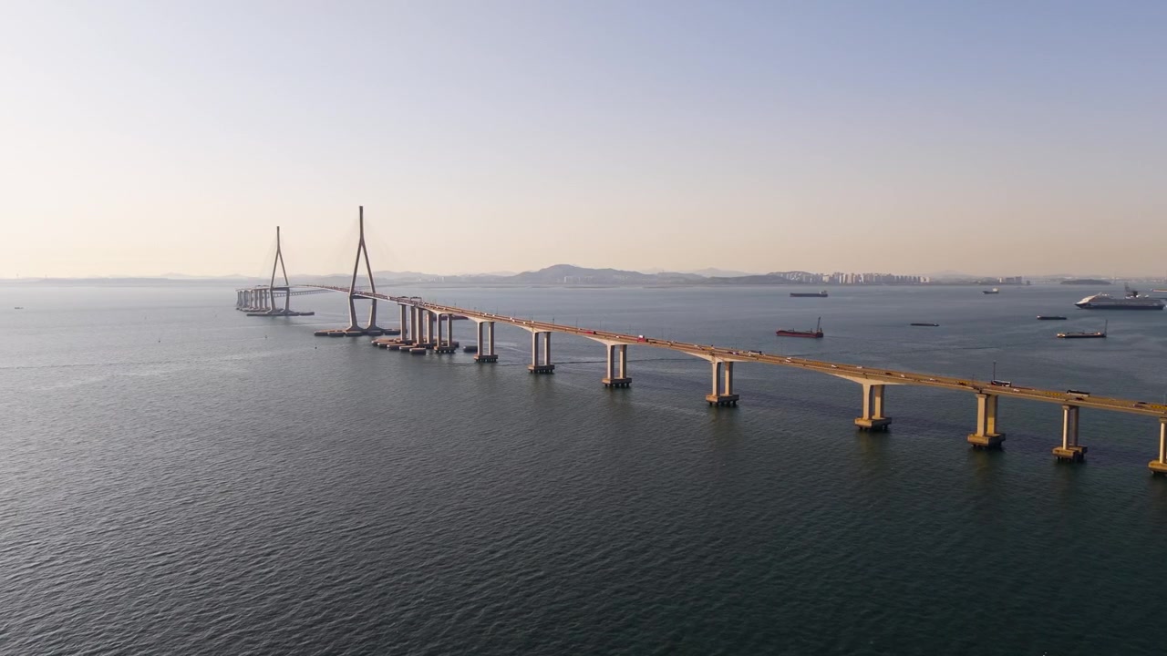 Vista aerea si avvicina al Ponte di Incheon mentre il traffico attraversa il mare calmo con navi da carico e lo skyline della città in Corea del Sud.