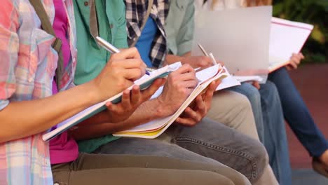 students sitting in a row writing in notebooks