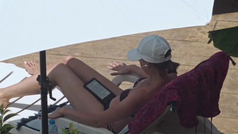 beautiful young women relaxing on the deck chair near the pool