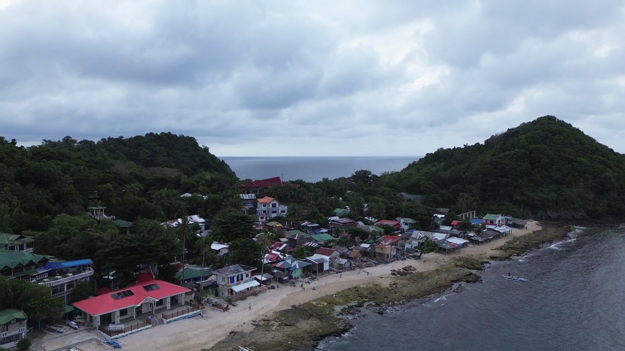 Aerial view of Apo Island village in the Philippines on a cloudy day showing remote tropical settlement coastal scenery and everyday island life in Southeast Asia
