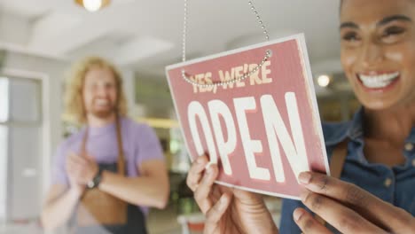 Happy-diverse-male-and-female-baristas-wearing-black-aprons-opening-coffee-shop