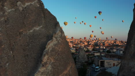 reveal shot from behind the rocks of hot air balloons over goreme cappadoica, turkey