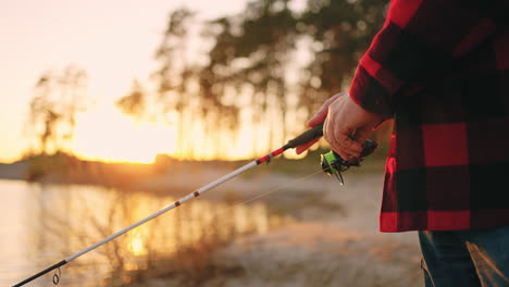 Fischer-Fängt-Allein-Bei-Sonnenuntergang-Oder-Sonnenaufgang-Fische.-Nahaufnahme-Der-Angelrute-In-Den-Händen.-Ruhige-Und-Aktive-Erholung-In-Der-Natur