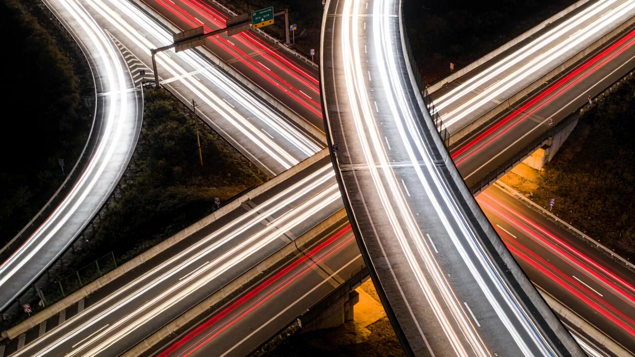 Catturando un'autostrada sopraelevata di notte mentre il traffico entra nelle rampe, creando scie di luce rosse e bianche.