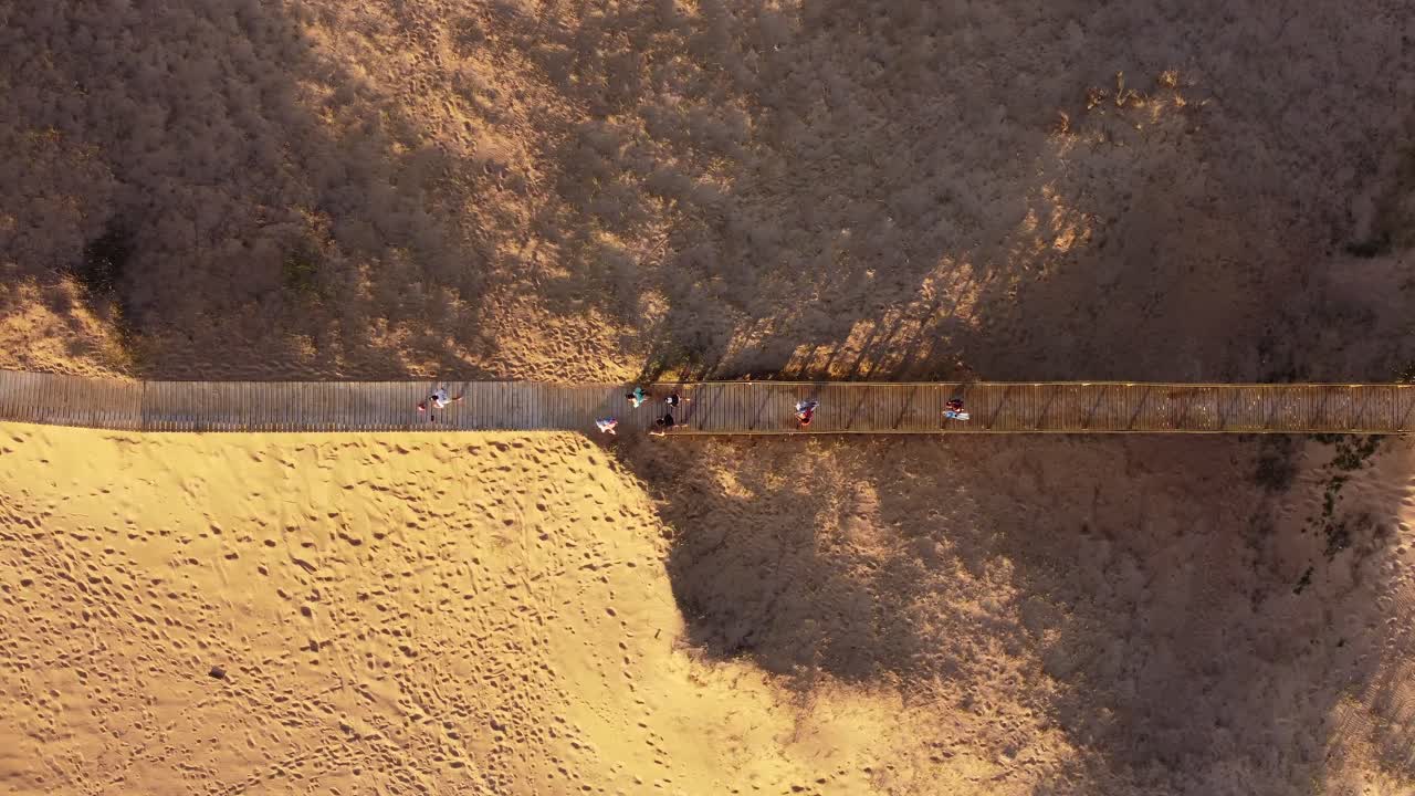 우루과이의 푼타 델 에스테(punta del este) 해변에서 나무 보행자 다리를 따라 걷는 사람들