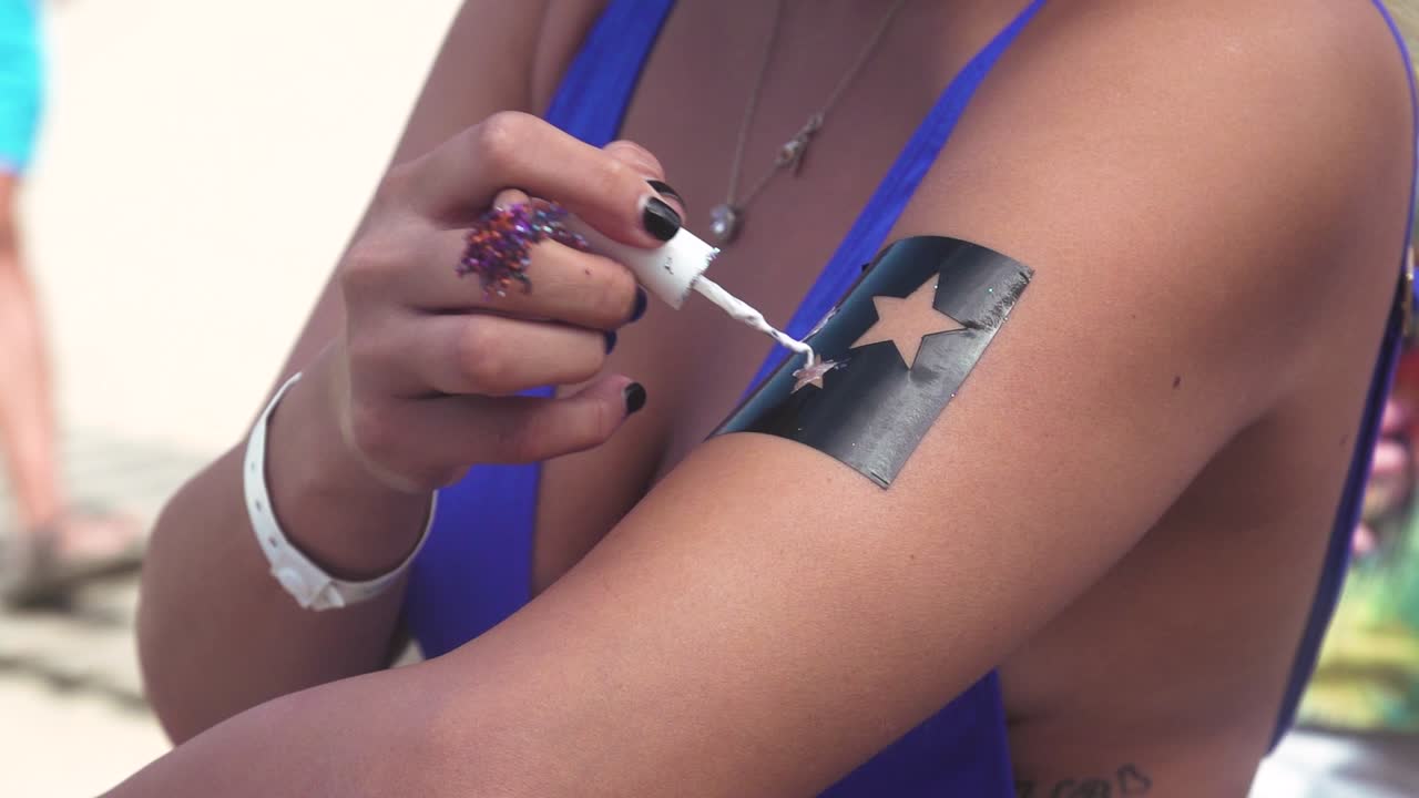 mujer con un vestido azul auto-pintado brazo con pintura estrella plantillas formato para fiesta de verano, cámara lenta