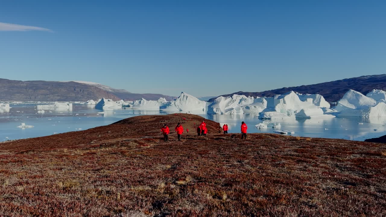 동부 그린란드의 빙산 근처에서 하이킹하는 관광객