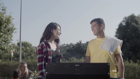 happy man and teenage daughter talking at barbecue grill