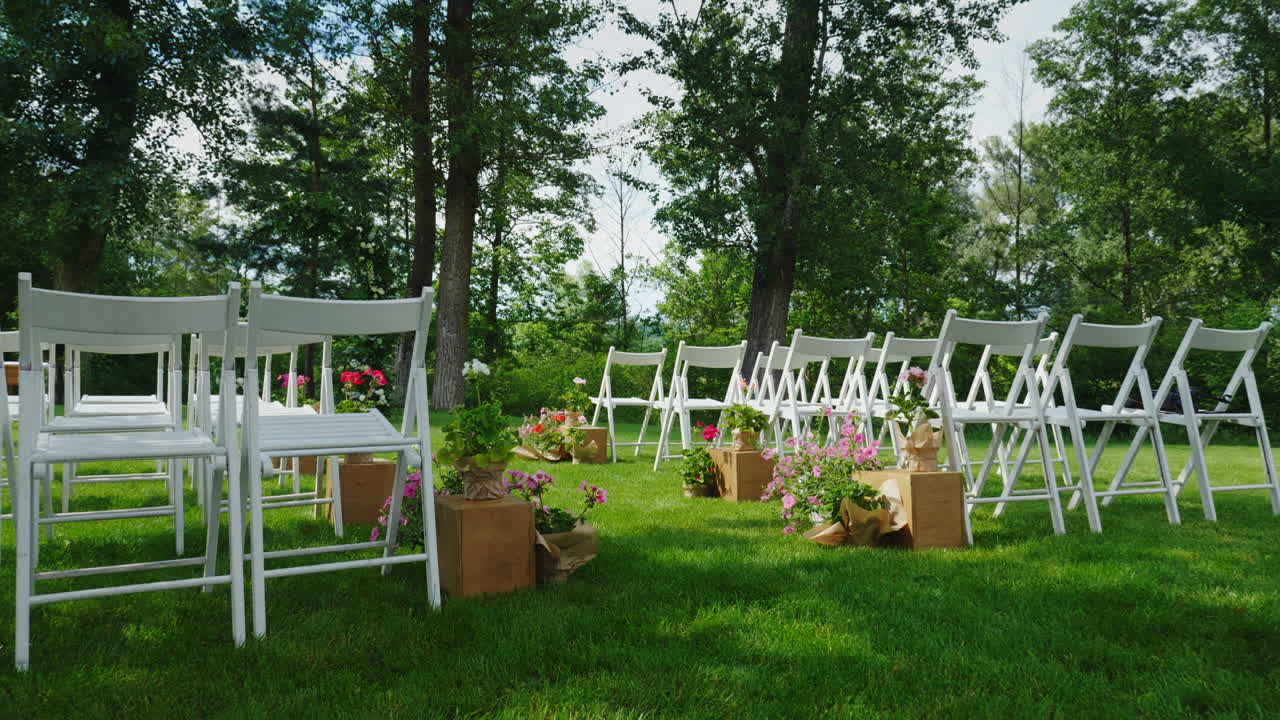 결혼식을 위한 흰색 나무 의자가 줄지어 있는 녹색 잔디밭