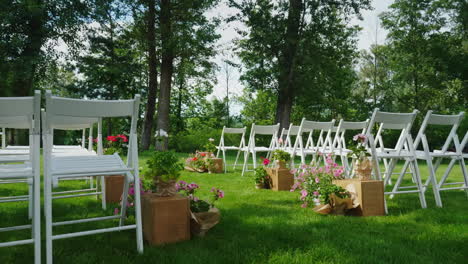 green lawn with rows of white wooden chairs place for the wedding ceremony