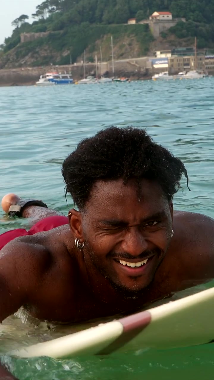 Giovane uomo che fa l'occhiolino mentre fa surf nell'oceano