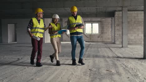 Wide-shot-of-busy-caucasian-engineers-walking-across-the-construction-site.