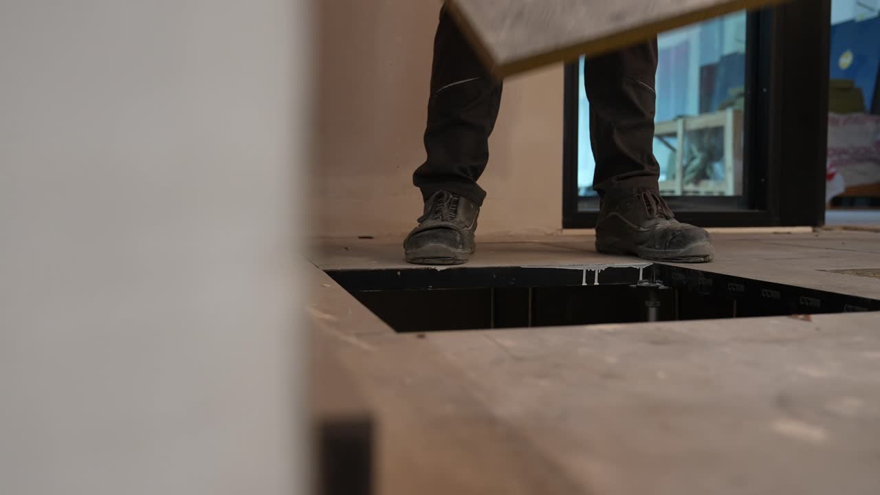 Byggepladsens gulvlægger afslutter lægningen af spånpladegulvet.