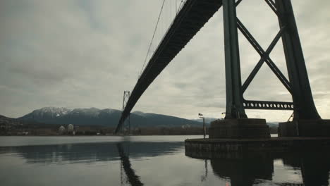 wide shot under lions gate suspension bridge in stanley park, vancouver, cloudy, slowmotion