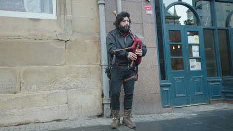 a street entertainer in edinburgh plays his bagpipes for watching tourists