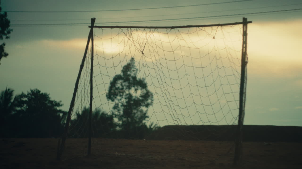 Goalpost standing on a field, empty, serene scene with distant nature, and cloudy sky