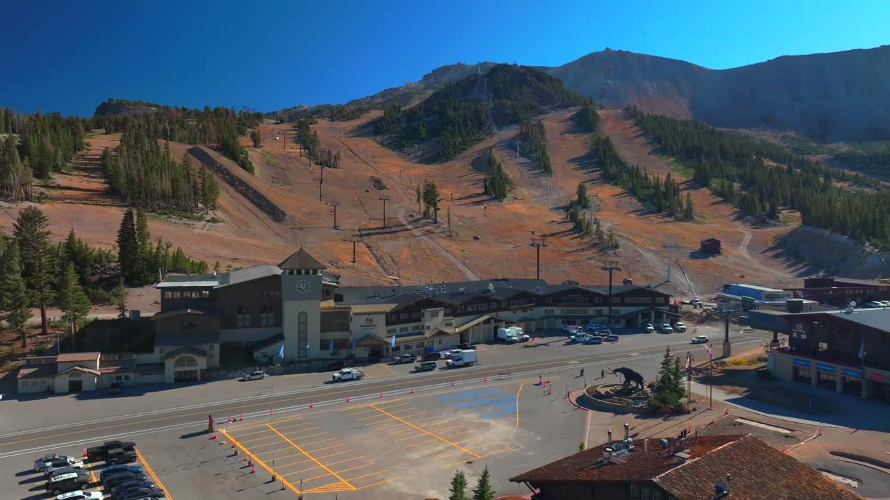 Mammoth Lakes Mountain Ski Area aerial drone California McCoy Station Main lodge Minarets Upper Panorama Gondola summer autumn fall car parking lot sunny blue sky chairlift gondola backwards pan up