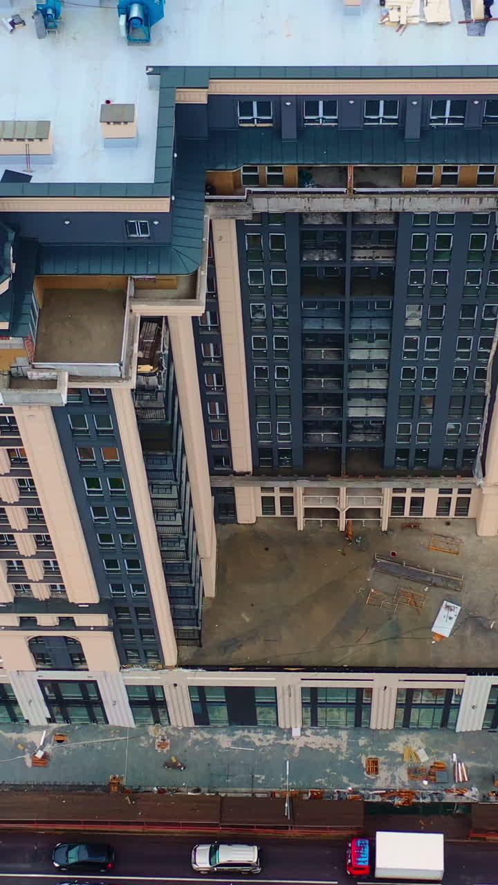 Building of multi-storey architecture. Modern tall apartment building under construction in the city. Aerial view. Vertical video