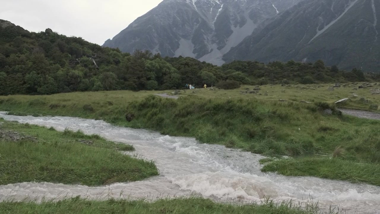 山からの激しい川の氾濫が緑の野原に洪水を引き起こす