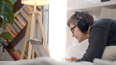 woman working on laptop in bed with headphones