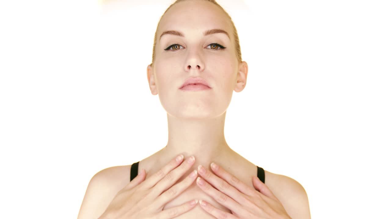 mujer bonita semidesnuda en 20s pelo tocando su cuello aislado sobre fondo blanco.