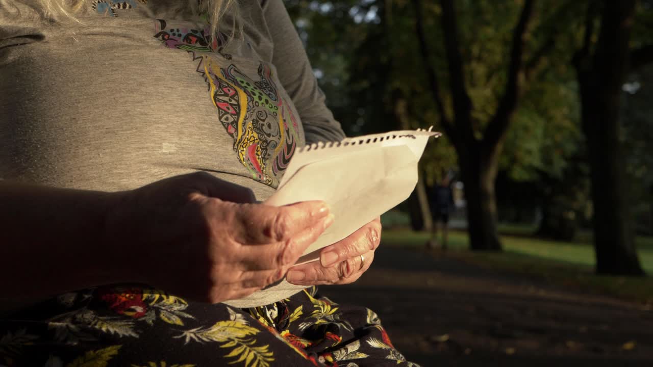 Donna matura che legge una lettera nel parco, ripresa con zoom