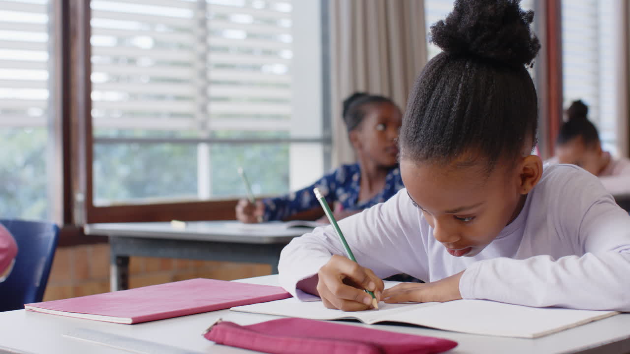 In school, girl writing in notebook at desk, concentrating on her work