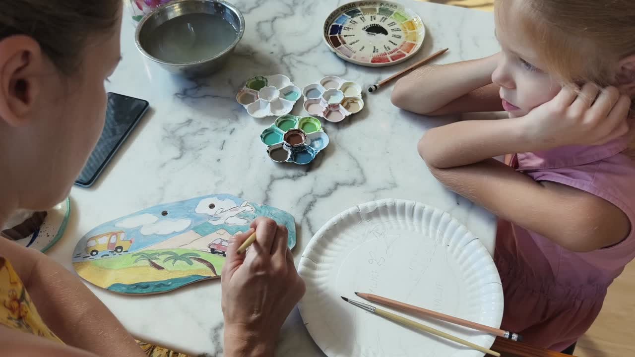 madre e hija pintando una placa de cerámica