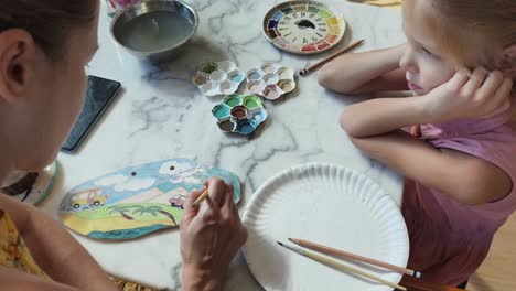 mother and daughter painting a ceramic plate