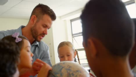 maestro masculino caucásico enseñando a sus hijos sobre el globo en el aula 4k