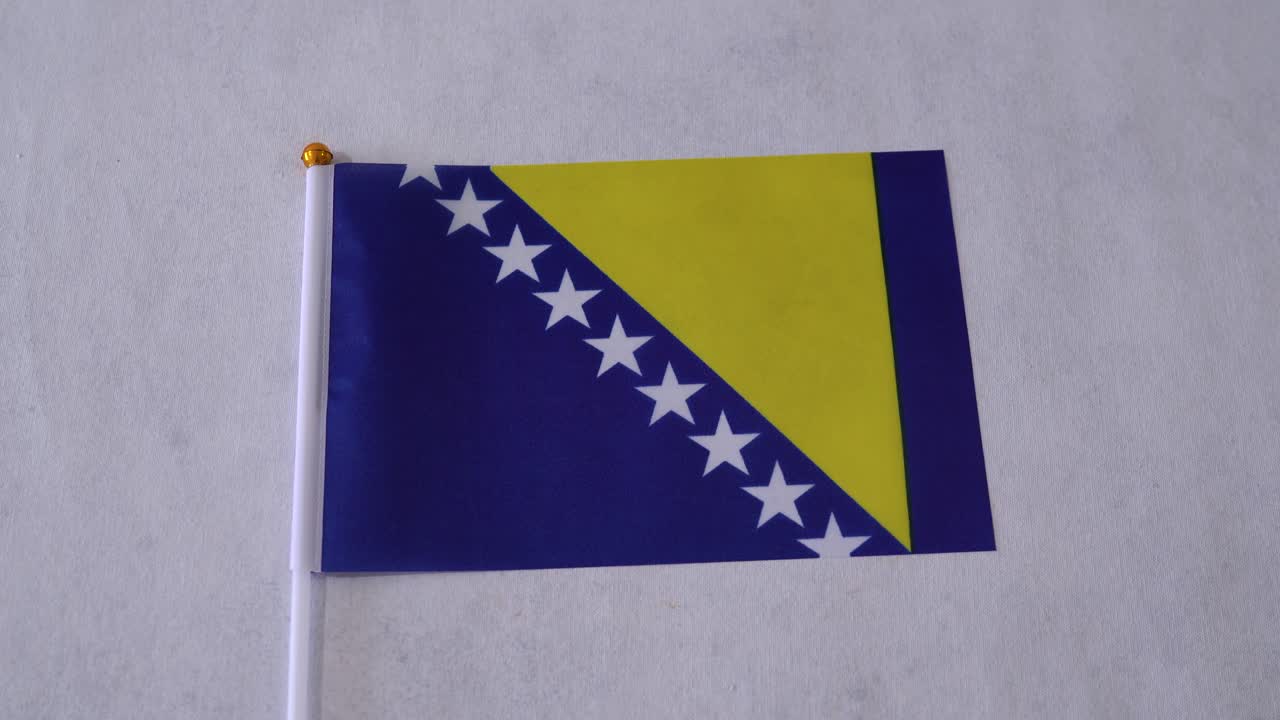 Primo piano della bandiera della Bosnia ed Erzegovina su sfondo bianco. Bandiera nazionale bosniaca.