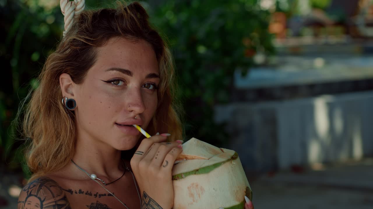 열대 해변 에서 코코 물 을 마시는 여자